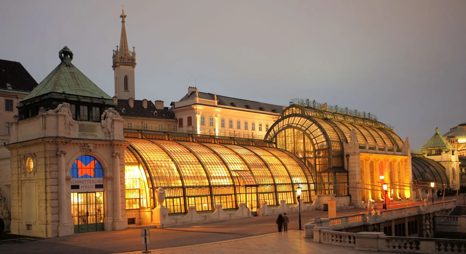 Das Schmetterlinghaus im Jugendstil-Palmenhaus der Hofburg, warm beleuchtet in der Abenddämmerung